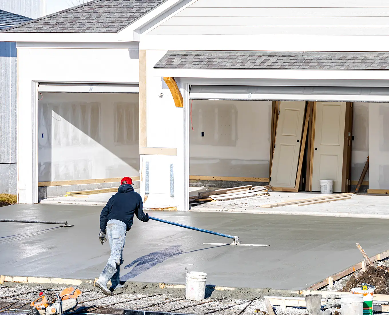 workers smoothing out concrete for driveway for new house in canton ga